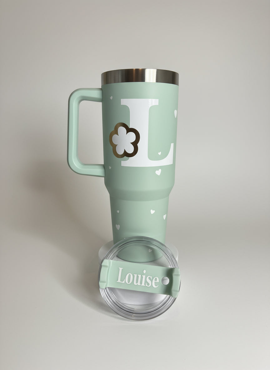 Mint green travel mug with a handle and 'Louise' branding on a light gray background