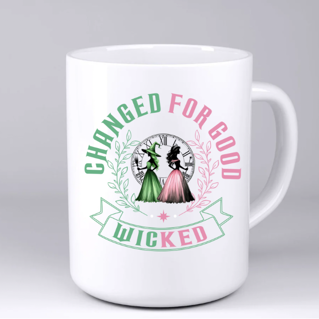White mug with 'Wicked' themed design featuring two witches and text on a gray background